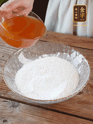 轉(zhuǎn)化糖漿、枧水、花生油攪拌均勻，加入面粉混合，醒發(fā)2小時。捏成23g一個的小球